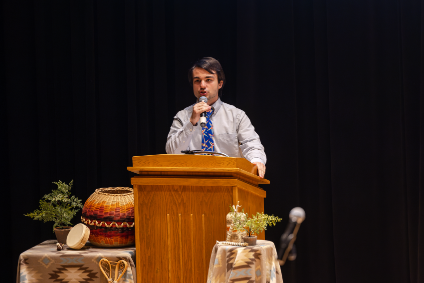 Toby Martin speaks behind a podium at the MAIOSU Pageant
