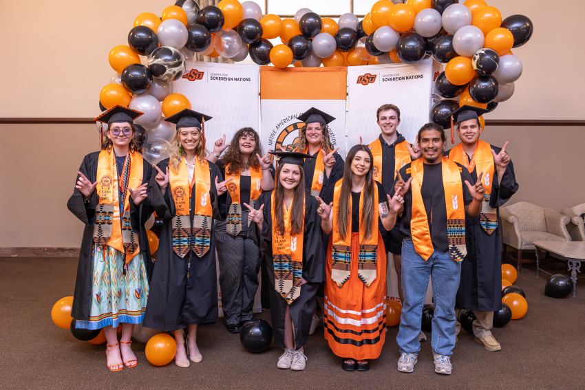 NASA students pose in graduation stoles in front of orange and black balloon arch with NASA students pose in graduation stoles in front of orange and black balloon arch with