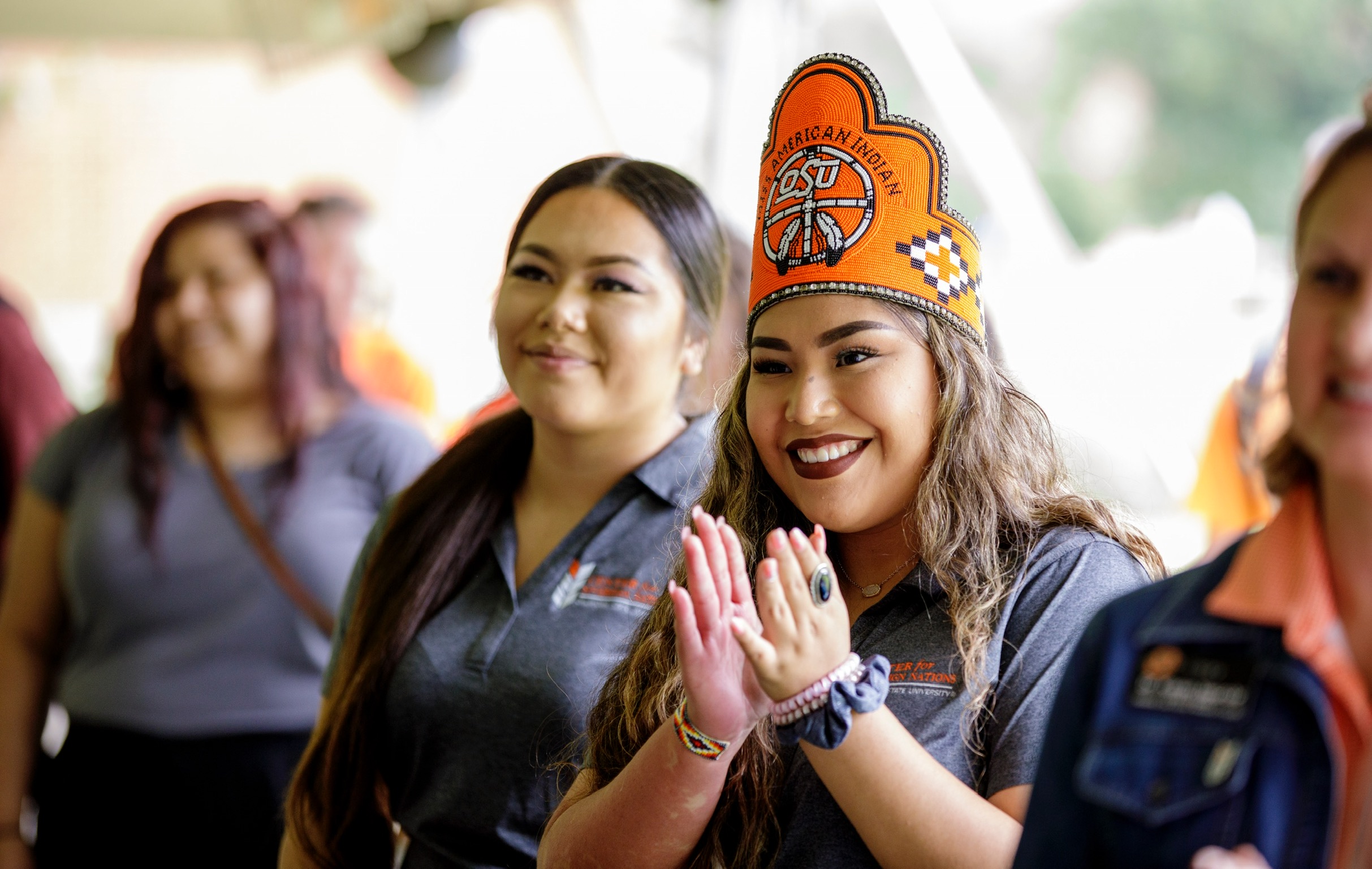 Miss American Indian OSU MaCaylin pictured in a candid photo, smiling and clapping, wearing the MAIOSU crown.