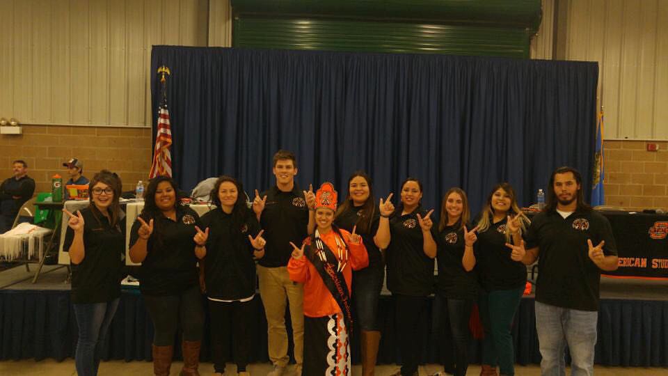 Miss American Indian OSU pictured wearing Southern Cloth regalia, smiling in a group photo with NASA executive members.