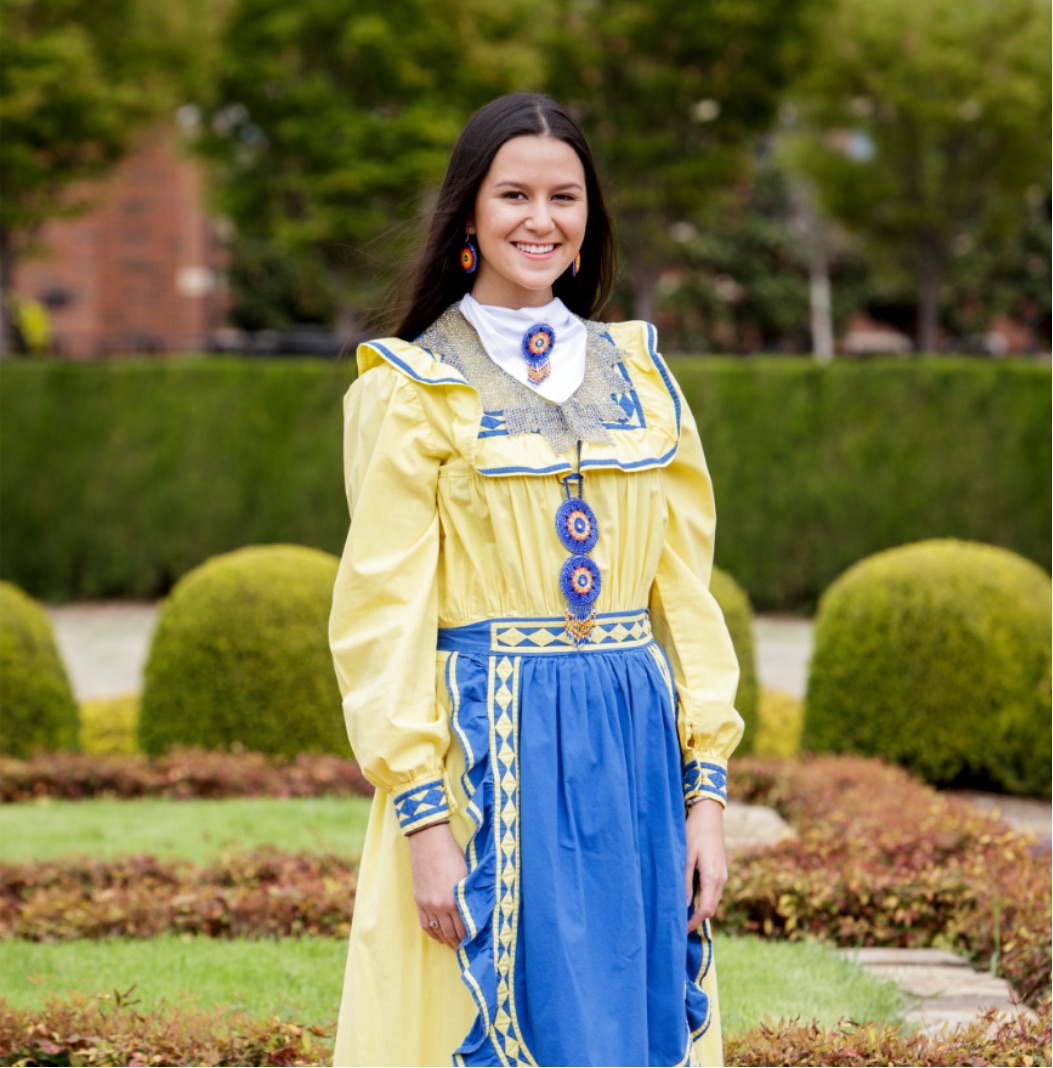 Miss American Indian OSU Cathrine wearing yellow and blue choctaw tradional dress in OSU gardensPictured