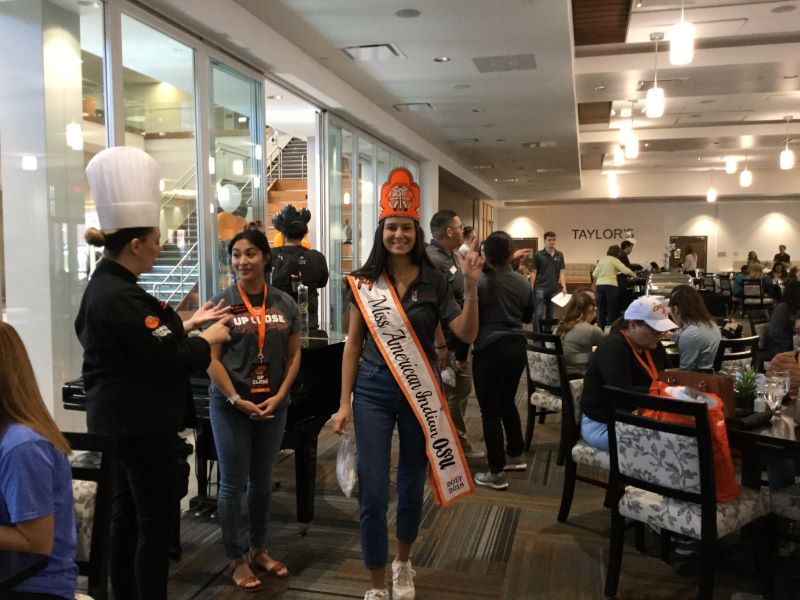 Miss American Indian OSU Cathrine pictured smiling at the camera at an event in Taylor’s Restaurant on campus, with NASA executive members.
