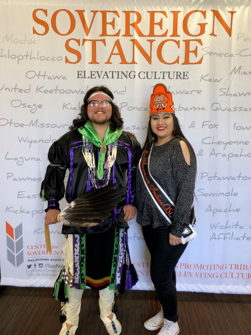 Miss American Indian OSU Cydney and Mr American Indain OSU Che Pictured posing in front of Center for Soverign Nation pop up banner