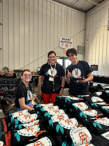 Jenna, Sky, and Ike at Powwow working T-shirt table