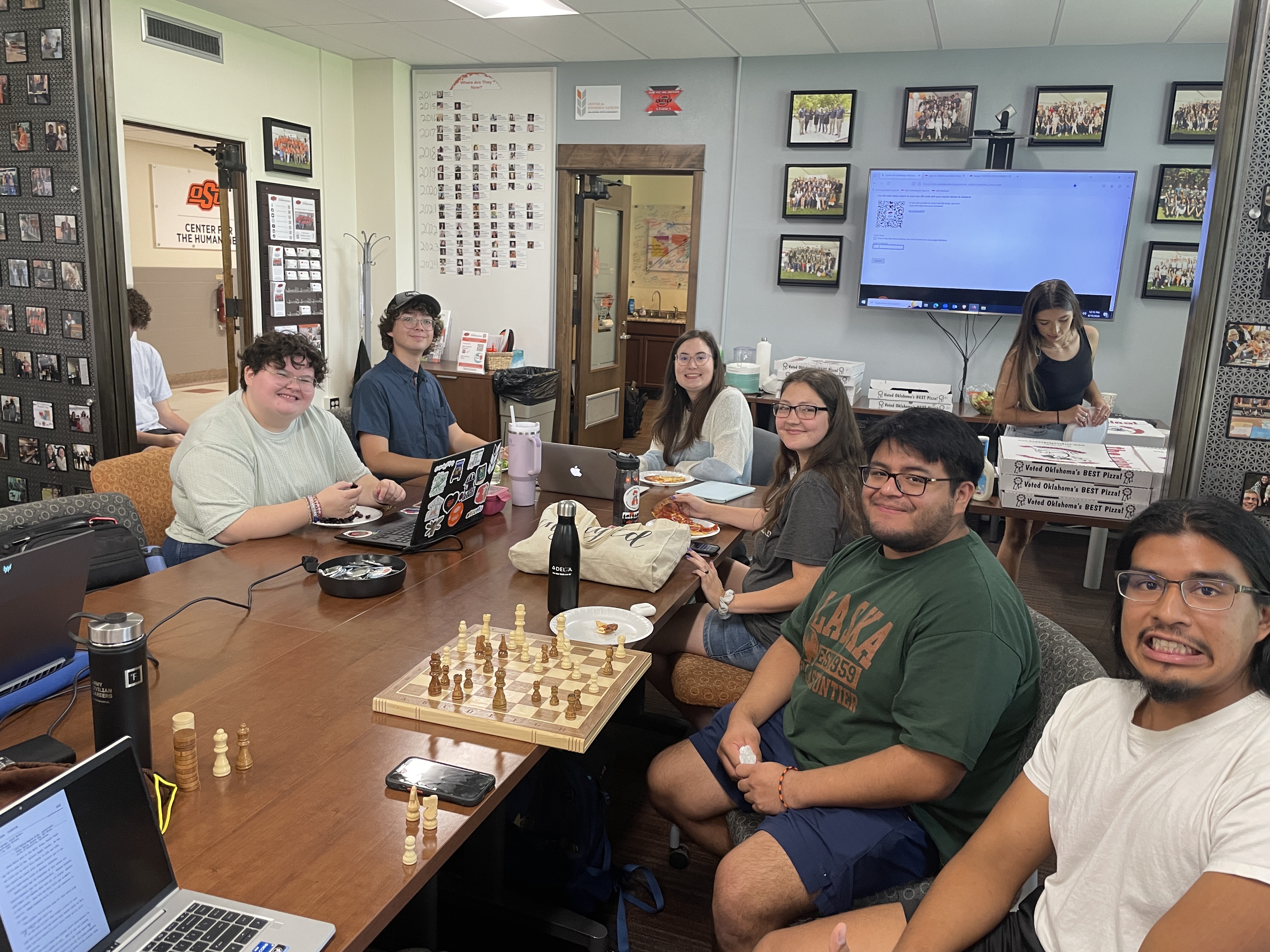 A group of students sitting around a rectangular table playing various games.