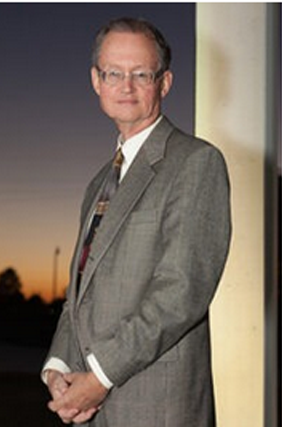 Dr. Bob Blackburn standing next to a wall in front of a sunset.